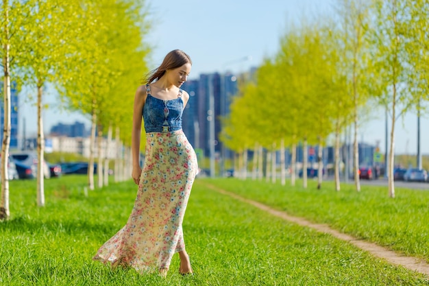 Retrato feliz hermosa mujer joven relajante en el parque en vestido largo alegre