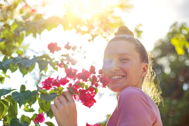 Retrato de feliz hermosa niña joven mujer positiva está oliendo hermosas flores amarillas en el jardín sonriendo disfrutando de la primavera o el día de verano respirando profundamente aire fresco