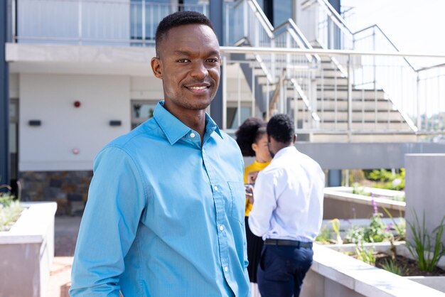 Retrato de un feliz hombre de negocios afroamericano con diversos colegas en el fondo. Negocios globales, finanzas y concepto de oficina.