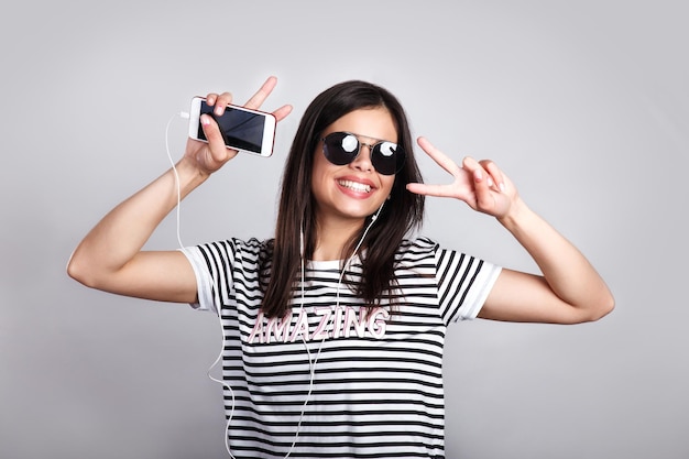 Retrato feliz humor de verão de uma jovem alegre com longos cabelos morenos em óculos de sol