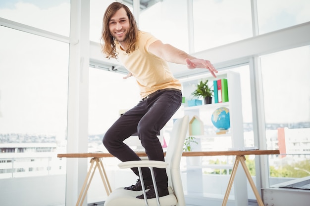 Retrato de feliz inconformista de pie en la silla en la oficina