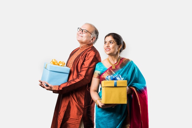 Retrato de feliz indio asiático senior o pareja jubilada sosteniendo cajas de regalo aisladas sobre fondo blanco.