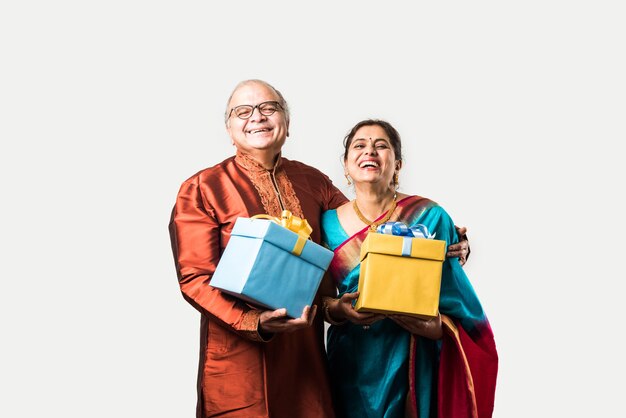 Retrato de feliz indio asiático senior o pareja jubilada sosteniendo cajas de regalo aisladas sobre fondo blanco.