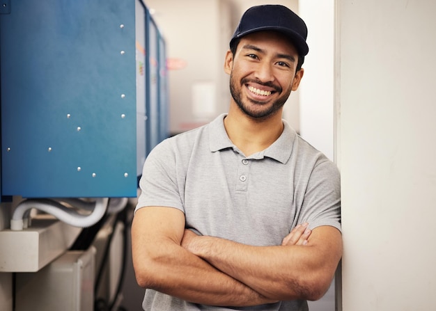 Retrato feliz de ingeniero y reparador en el trabajo para el servicio de mantenimiento y control de inspección Técnico masculino con los brazos cruzados y una sonrisa en una sala para ingeniería de máquinas o fuente de alimentación