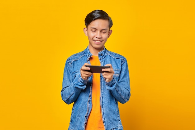 Retrato de feliz joven asiático jugando videojuegos en el teléfono móvil