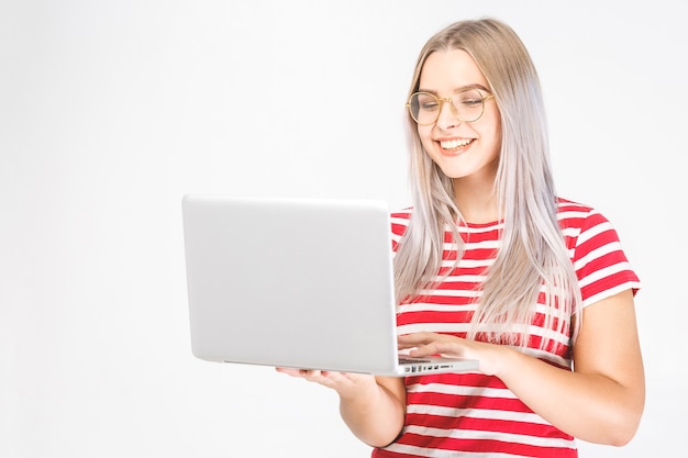 Retrato de feliz joven bella mujer sorprendida de pie con portátil aislado sobre fondo blanco. Espacio para texto.