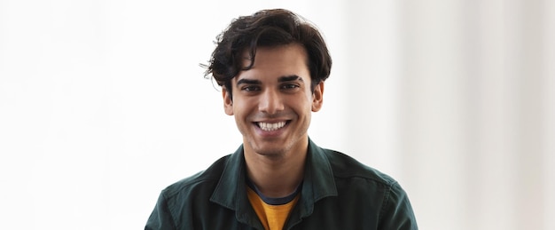 Foto retrato de feliz joven caucásico mirando a la cámara y sonriendo