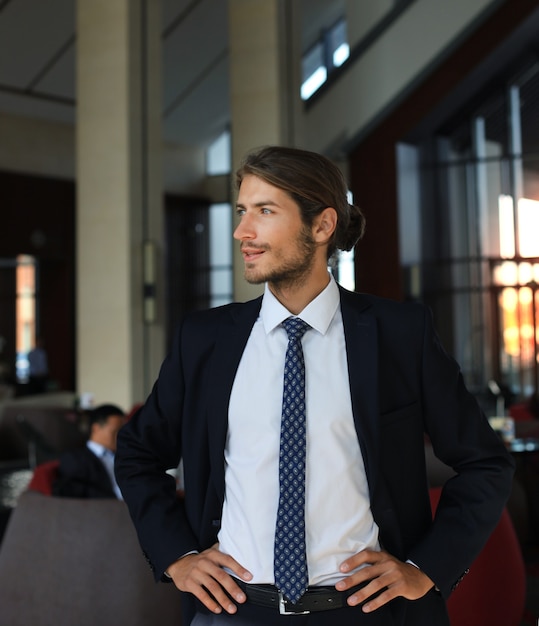 Retrato de feliz joven empresario de pie en el vestíbulo del hotel.