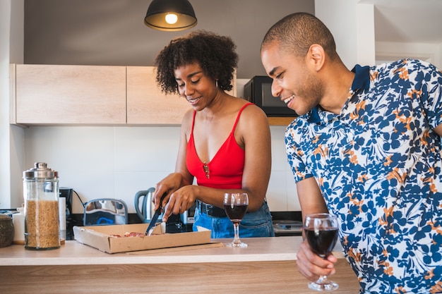 Retrato de feliz joven pareja latina disfrutando y cenando en casa nueva. Concepto de estilo de vida y relación.