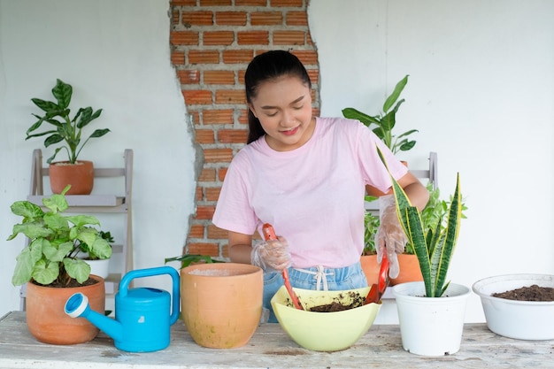 Retrato feliz joven plantar un árbol en maceta en casa chica asiática