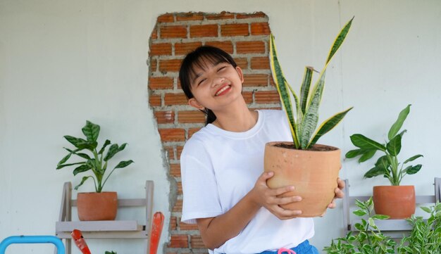 Retrato feliz joven con plantas verdes en casa chica asiática