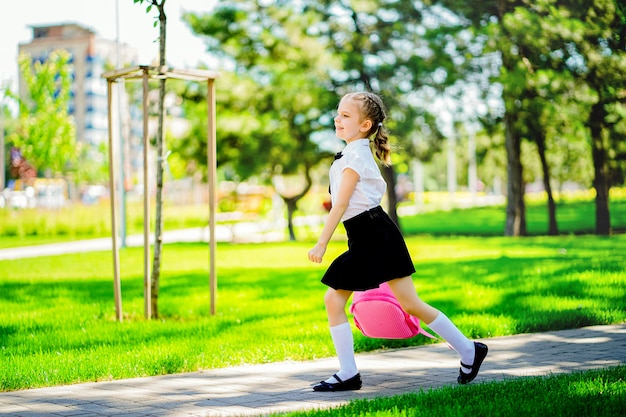 Retrato de feliz joven sonriente con mochila escolar fuera de la escuela primaria