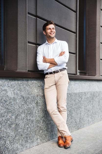 Retrato de un feliz joven vestido formal hombre inclinado