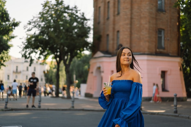 Retrato feliz joven vistiendo un vestido azul y bebiendo limonada cóctel de verano