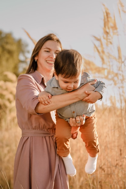 Retrato de feliz madre amorosa abrazando a su hijo en el parque soleado cerca del río