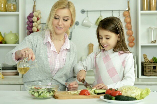 Retrato de feliz madre e hija cocinando en la cocina