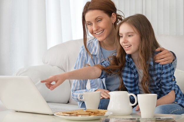 Retrato de una feliz madre e hija con portátil