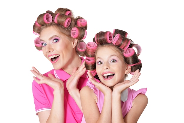 Retrato de feliz madre e hija en rizadores de pelo en estudio