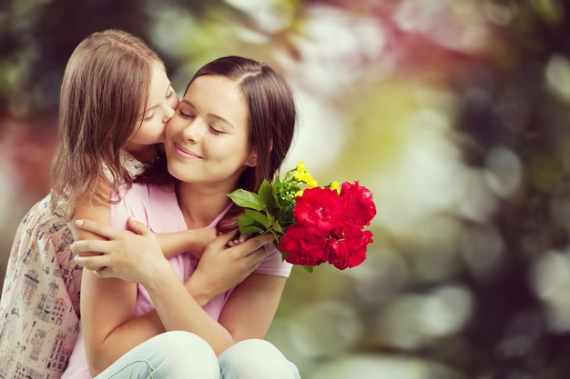 Retrato de feliz madre e hija sosteniendo flores
