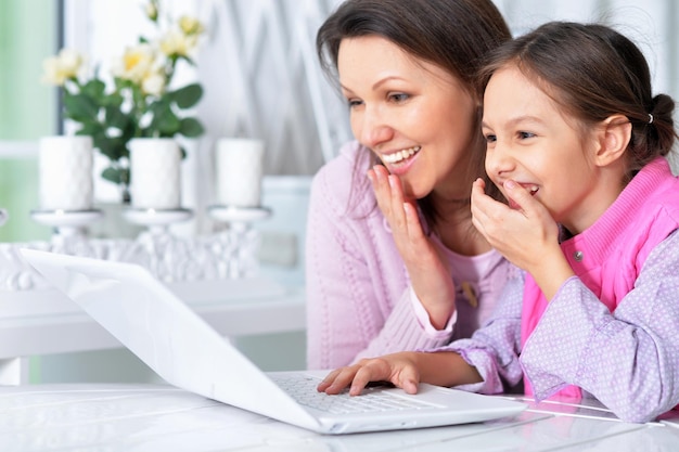 Retrato de feliz madre e hija usando laptop juntos