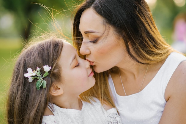 Retrato de una feliz madre e hija en el verano en el parque Una madre besa a su hija Familia feliz Feliz Día de la Madre Una postal para el Día de la Madre