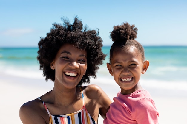 Retrato de una feliz madre y hija afroamericanas disfrutando de un día soleado en la playa