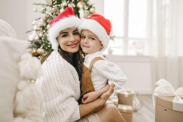 Retrato de feliz madre y su hijo celebran la Navidad en una sala decorada festivamente