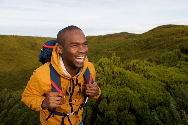 Retrato de un feliz mochilero afroamericano caminando en la naturaleza