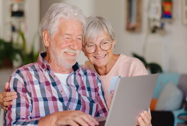 Retrato de una feliz y moderna pareja de ancianos navegando juntos en una computadora portátil para comprar en línea con tarjeta de crédito Alegre y hermosa pareja de ancianos de pelo blanco disfrutando del comercio electrónico