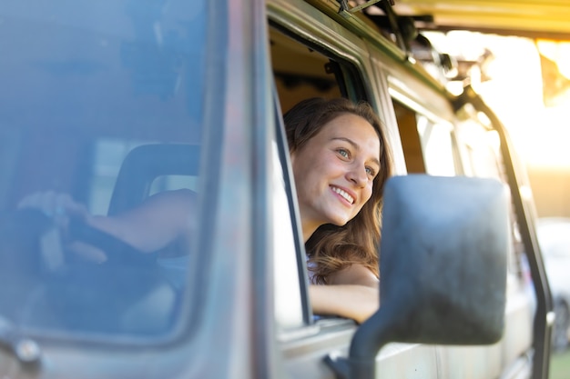 retrato feliz mujer caucásica conduce una vieja autocaravana vintage en la carretera. vacaciones de viaje familiar