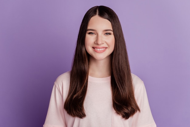 Retrato de feliz niña positiva con dientes sonrisa brillante en la pared púrpura