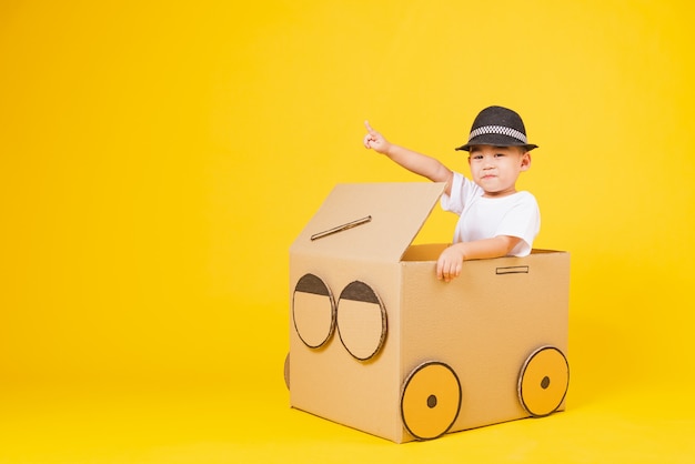 Retrato feliz niño asiático niños sonríe tan feliz conduciendo coche creativo por cartón y señalar con el dedo