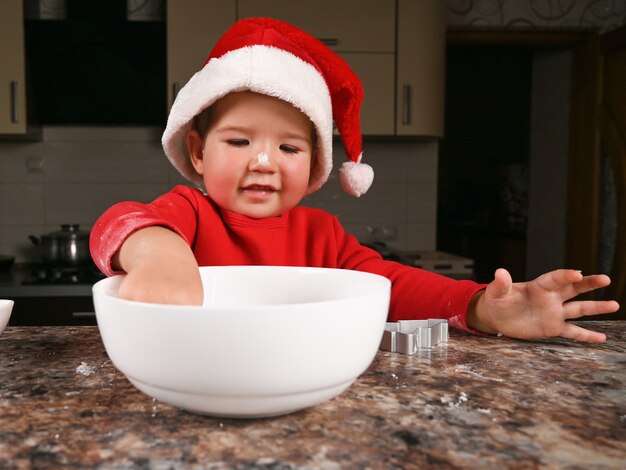Foto retrato de feliz niño caucásico en un gorro de papá noel en la cocina