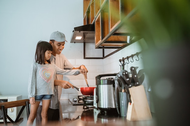 Foto retrato de feliz padre e hija asiáticos cocinando juntos en la cocina moderna