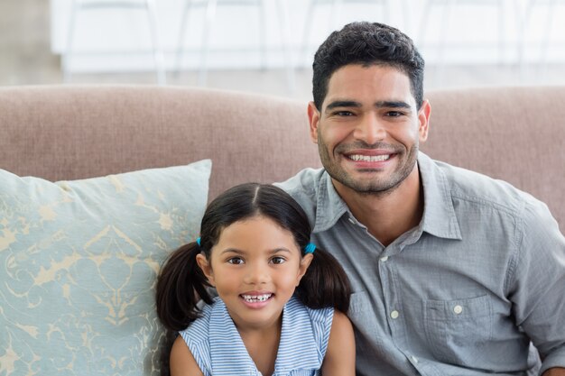 Retrato de feliz padre e hija sentada en el sofá en la sala de estar