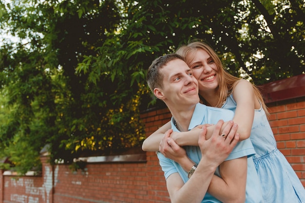 Retrato de la feliz pareja abrazándose riendo fondo de pared de ladrillos