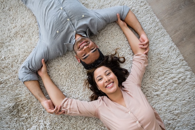 Retrato de la feliz pareja acostada en la alfombra en la sala de estar