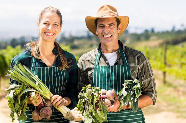 Retrato de la feliz pareja de agricultores con verduras de hoja