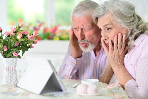 Retrato de una feliz pareja de ancianos usando una tableta en casa