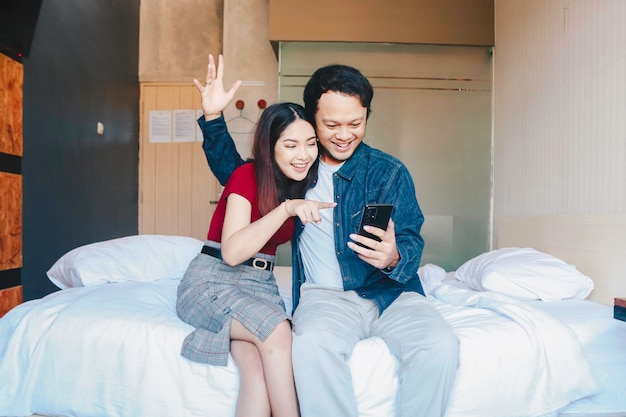 Un retrato de una feliz pareja asiática sonriendo a su teléfono inteligente