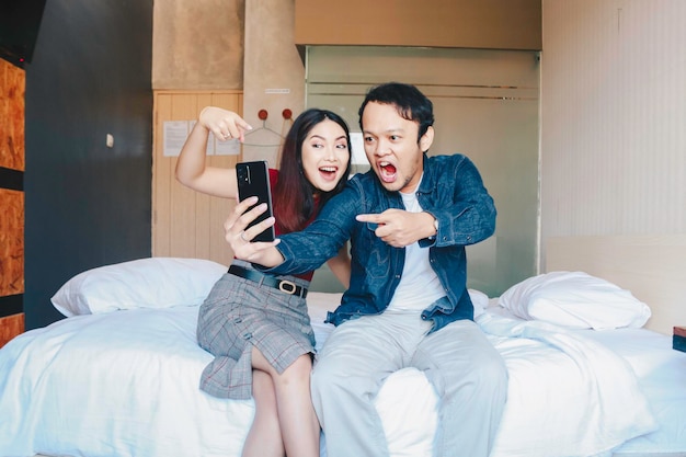 Un retrato de una feliz pareja asiática sonriendo a su teléfono inteligente