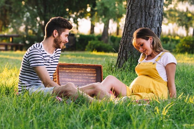 Retrato de una feliz pareja embarazada en un picnic.