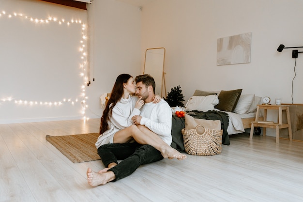 Retrato de una feliz pareja de enamorados abrazándose sentado en casa