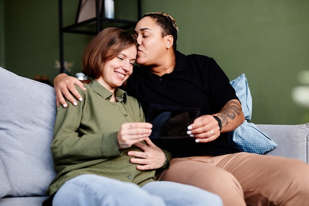 Retrato de feliz pareja gay con mujer joven embarazada mirando la imagen de ultrasonido del bebé del mismo sexo