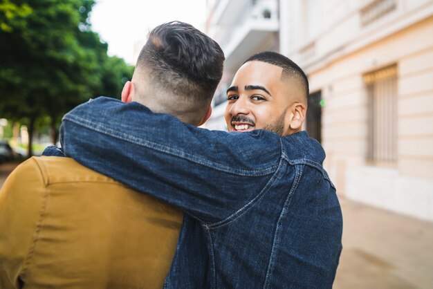 Foto retrato de feliz pareja gay pasar tiempo juntos y abrazarse en la calle. concepto de amor y lgbt.