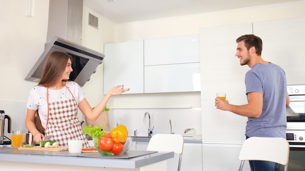 Retrato de feliz pareja joven cocinando juntos en la cocina de casa.