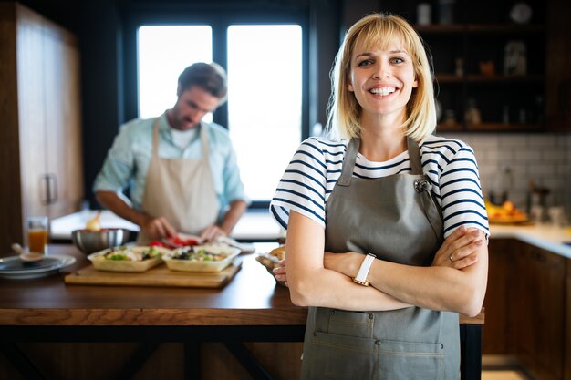 Retrato de feliz pareja joven cocinando juntos en la cocina de casa