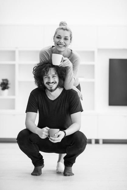 Retrato de una feliz pareja joven y hermosa abrazándose y bebiendo café en su nuevo hogar