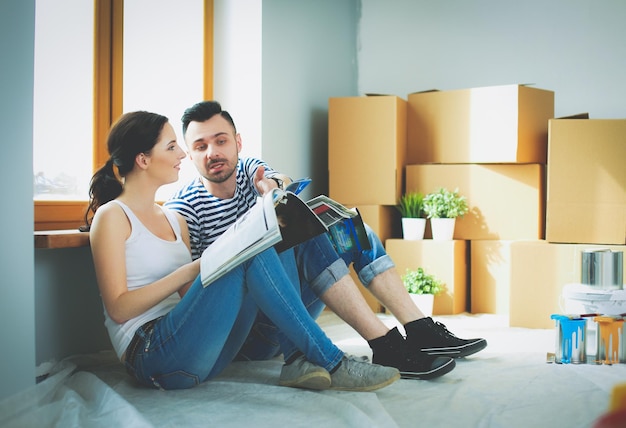 Retrato feliz pareja joven sonriente pintando la pared interior de la casa nueva pareja joven