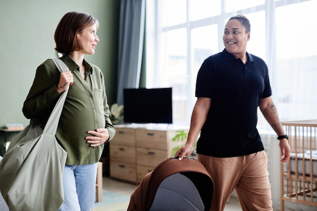 Retrato de feliz pareja lesbiana esperando bebé y dirigiéndose juntos al hospital de maternidad